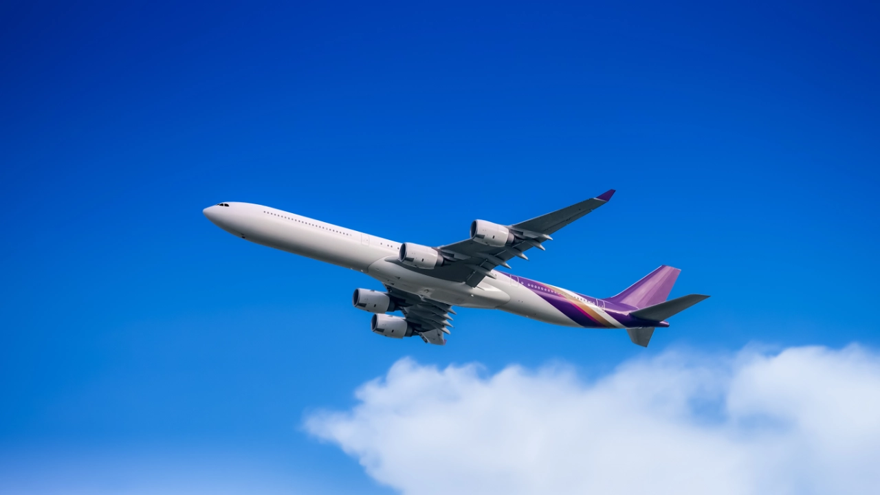 Fly fra Thai Airways flyver hen over en blå himmel