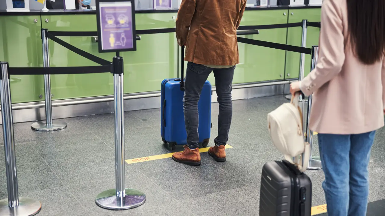 To personer venter i kø ved paskontrol i en lufthavn